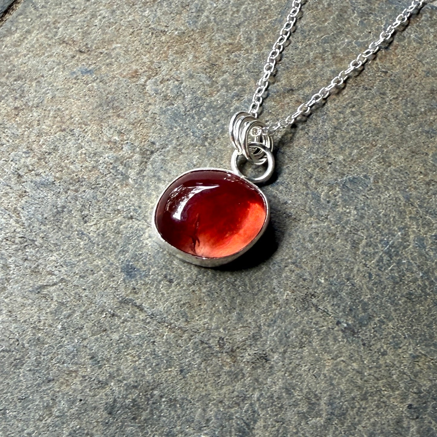 Necklace with a red oregon sunstone pendant on a stone surface
