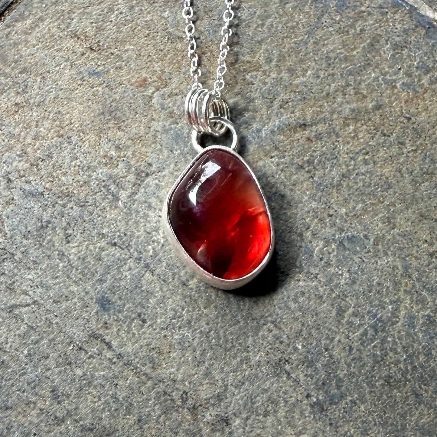 Necklace with a red oregon sunstone pendant on a gray stone surface