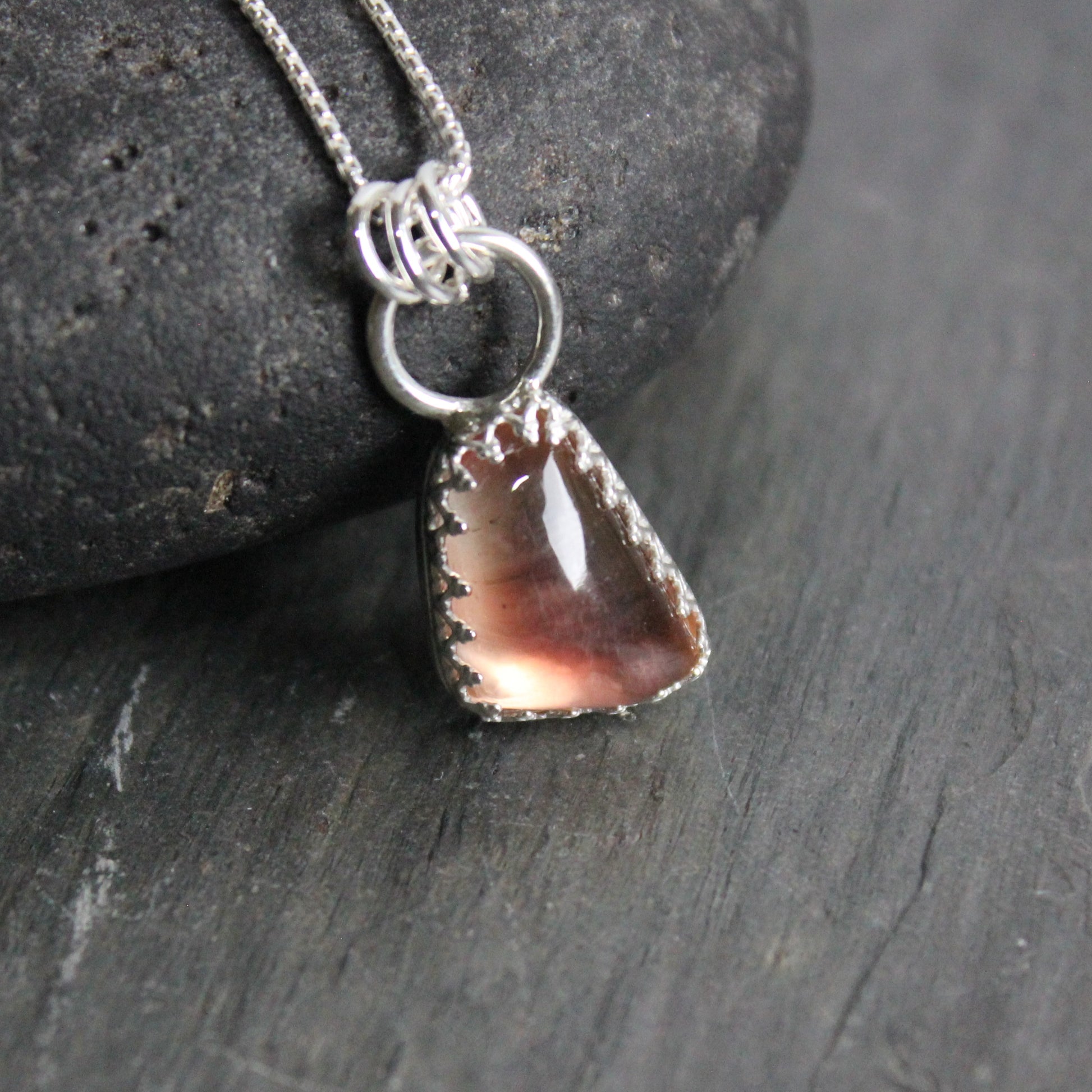 This is an approximately 12mm x 18mm Oregon sunstone with red and shiller throughout.  It has a fancy sterling silver bezel setting. 
