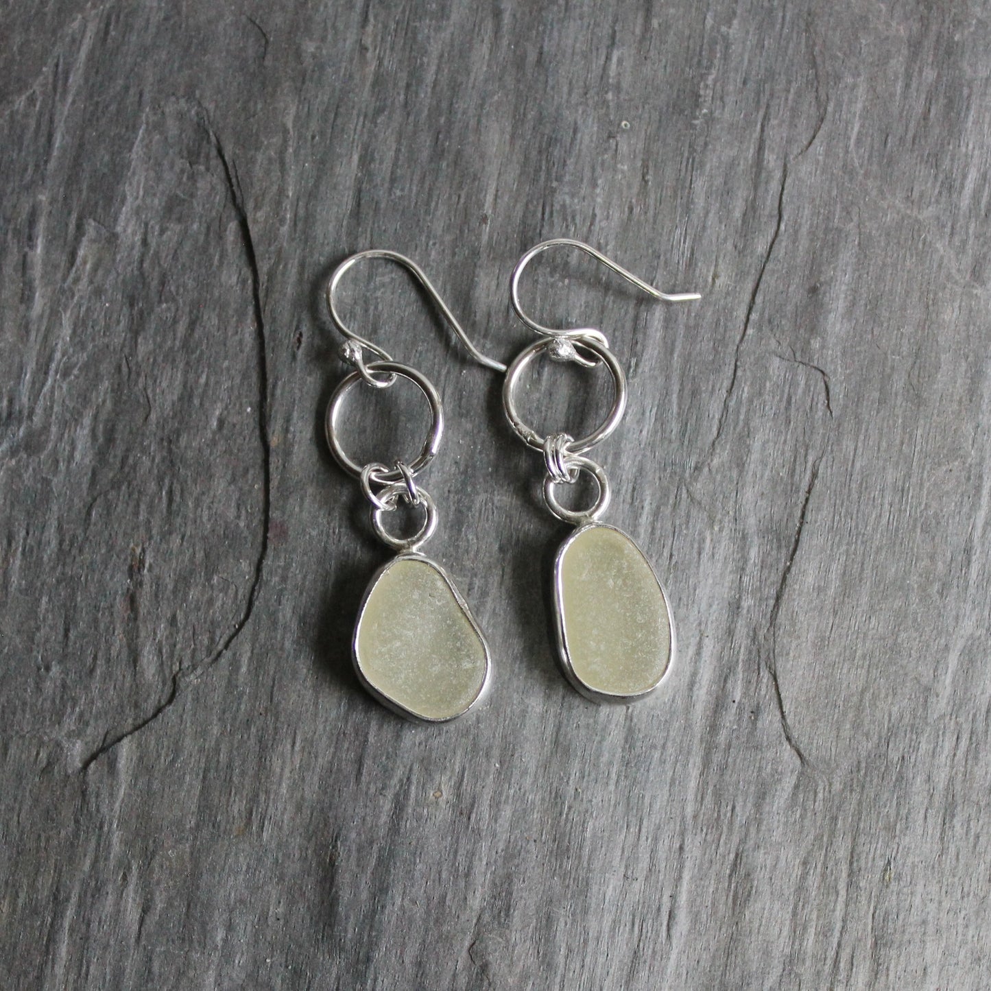These dangly earrings have pale yellow sea glass set in a fine & sterling silver bezel setting attached to a 10mm round link on handmade ear wires. 