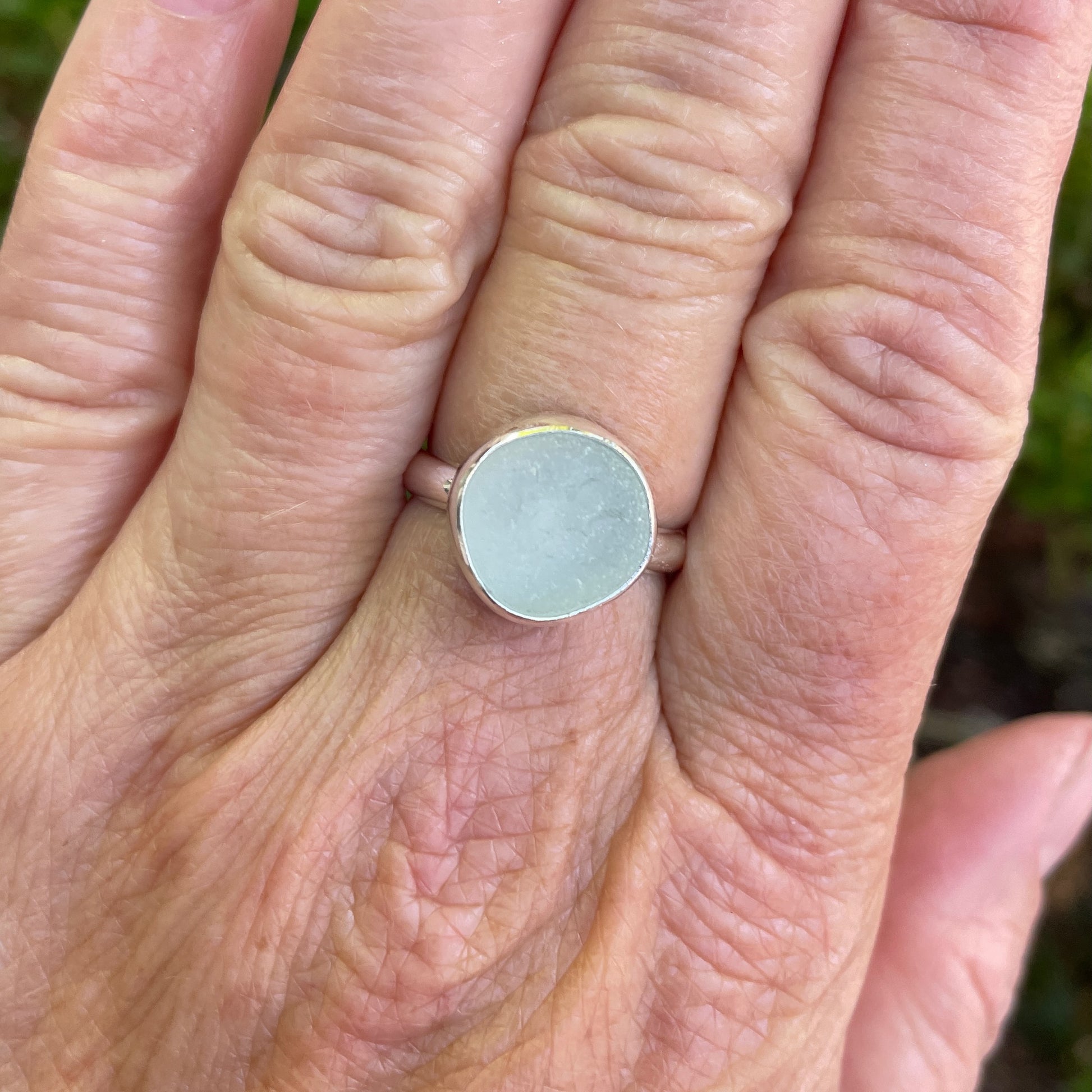 This is a chunky round piece of white sea glass set in a fine and sterling silver bezel setting with a hammered silver band.  Size 8 1/4 modeled on a hand