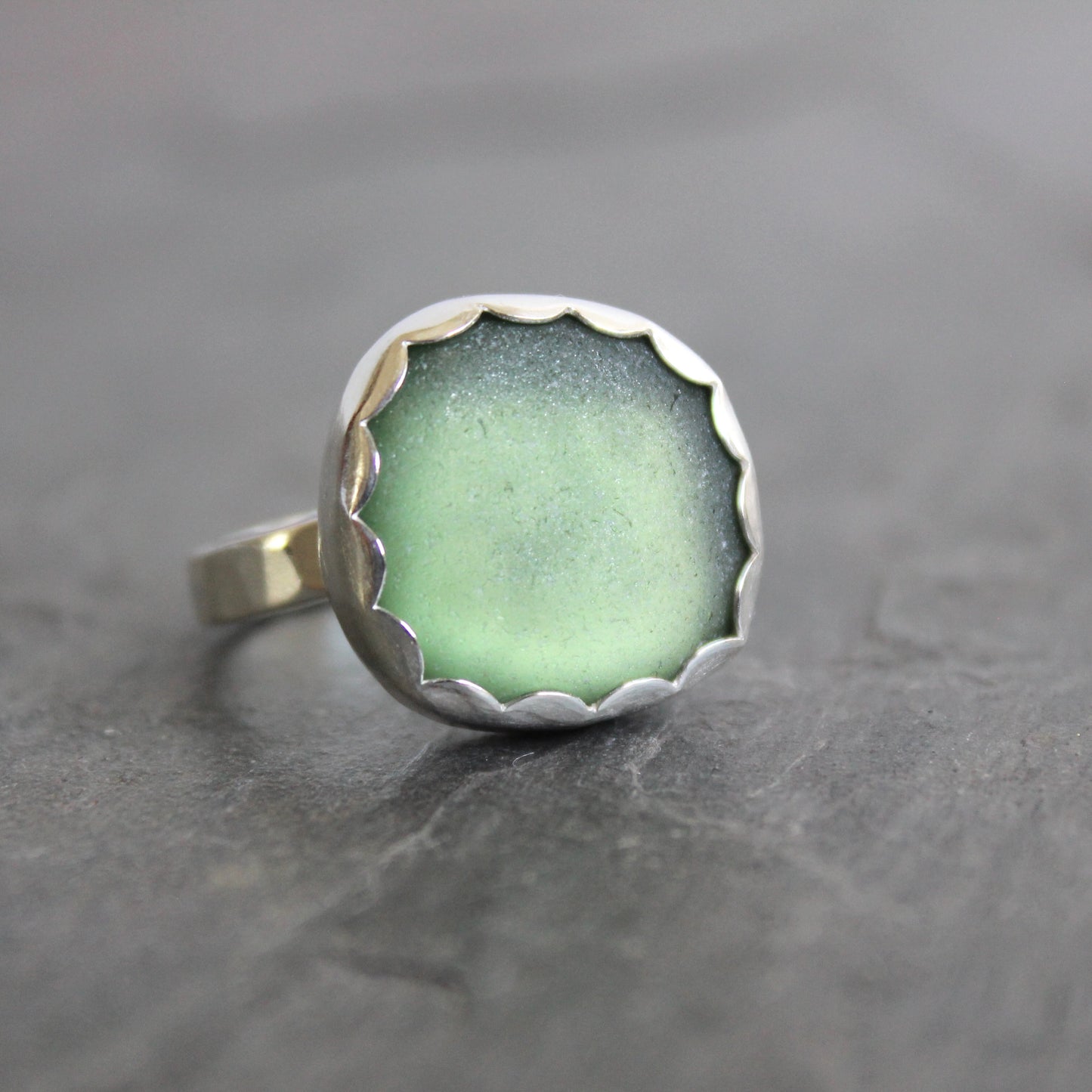 Ring with green sea glass and silver band on a gray surface