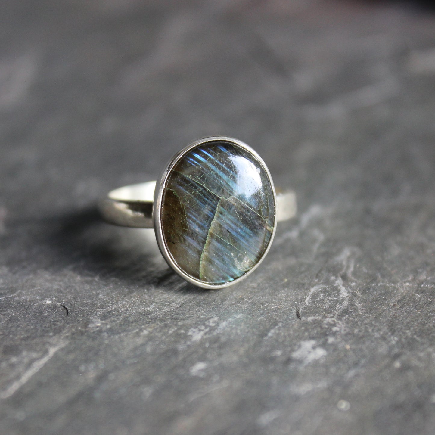 This ring has a small oval labradorite set in a fine & sterling silver bezel setting on a sturdy hammered band.  Size 12