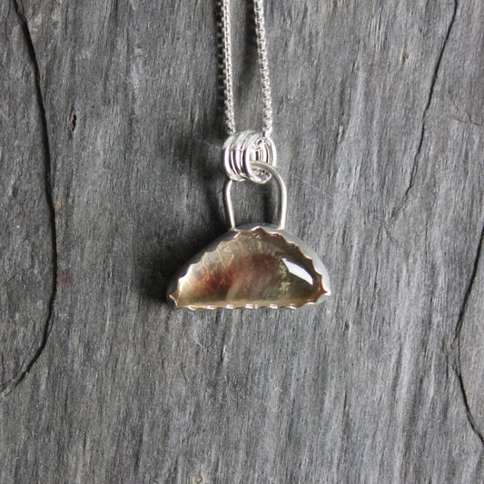 This is a triangular shaped Oregon sunstone that has some red, green and a little shiller.  It is set in a scalloped bezel setting and measures about 20mm x 10mm. 