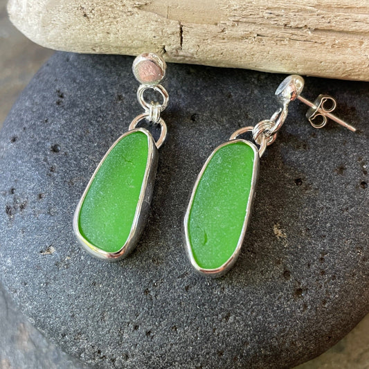 These dangly earrings have bright green oblong sea glass set in a fine and sterling silver bezel setting and attached to handmade recycled silver stud earrings. 