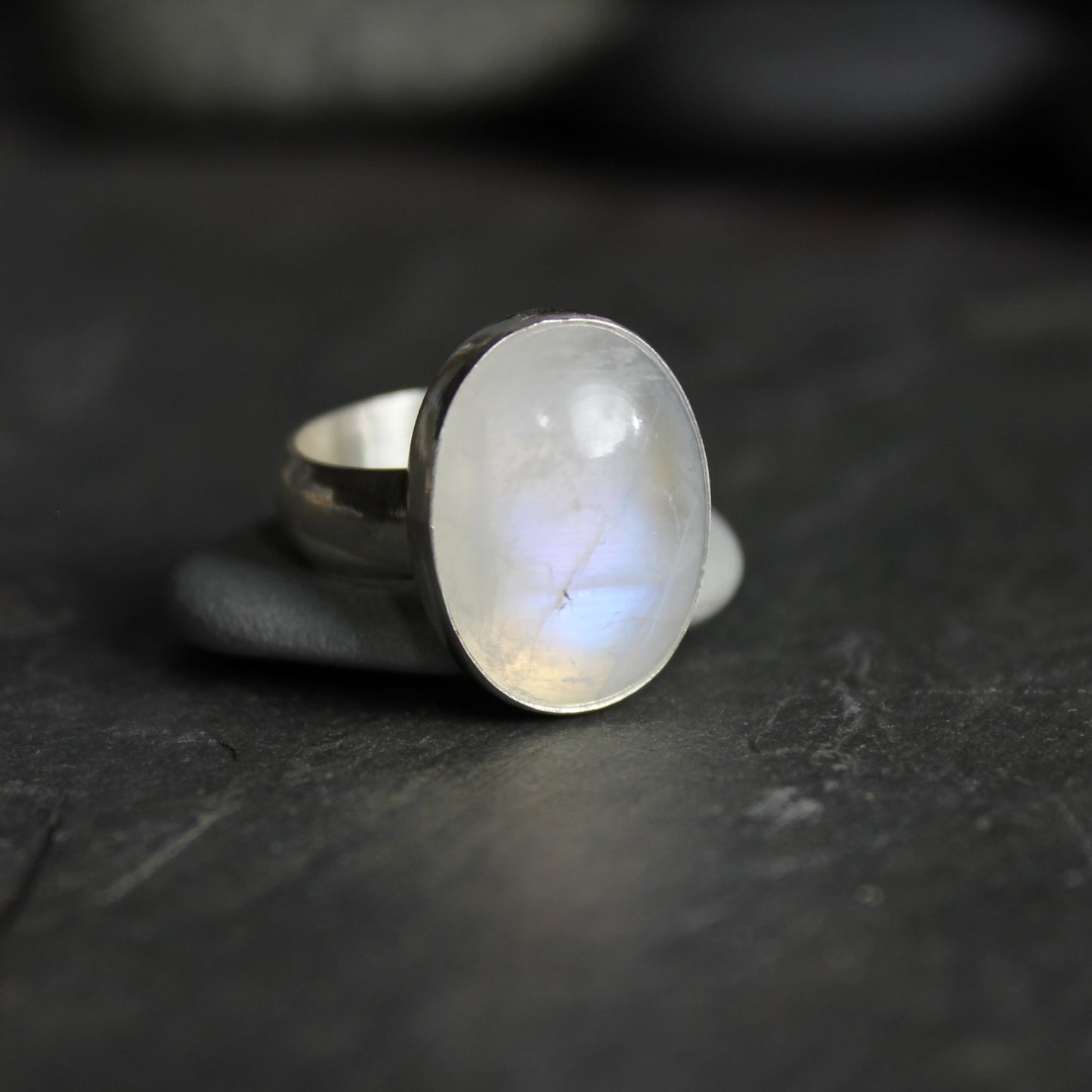 This is a large chunky rainbow moonstone cabochon set in a fine and sterling silver bezel setting on a sturdy hammered silver band. Size 7 1/2