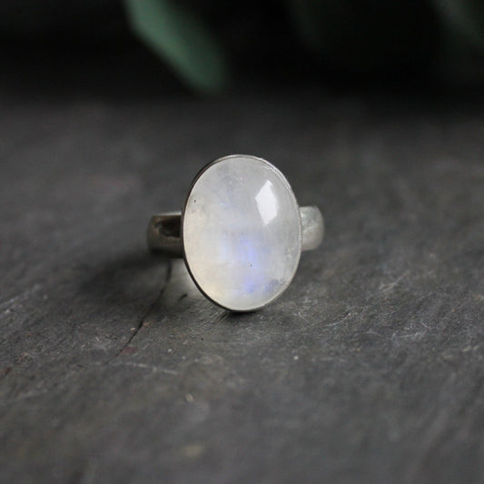 This is a huge rainbow moonstone statement ring with a large cabochon (15mm x 20mm) set in a fine and sterling silver bezel setting on a wide silver band.  Size 12 1/4