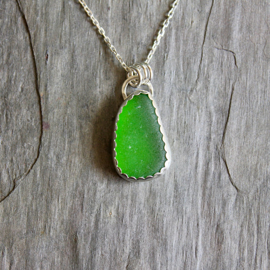 This is a large piece of lime green sea glass set in a fine and sterling silver scalloped bezel setting. 