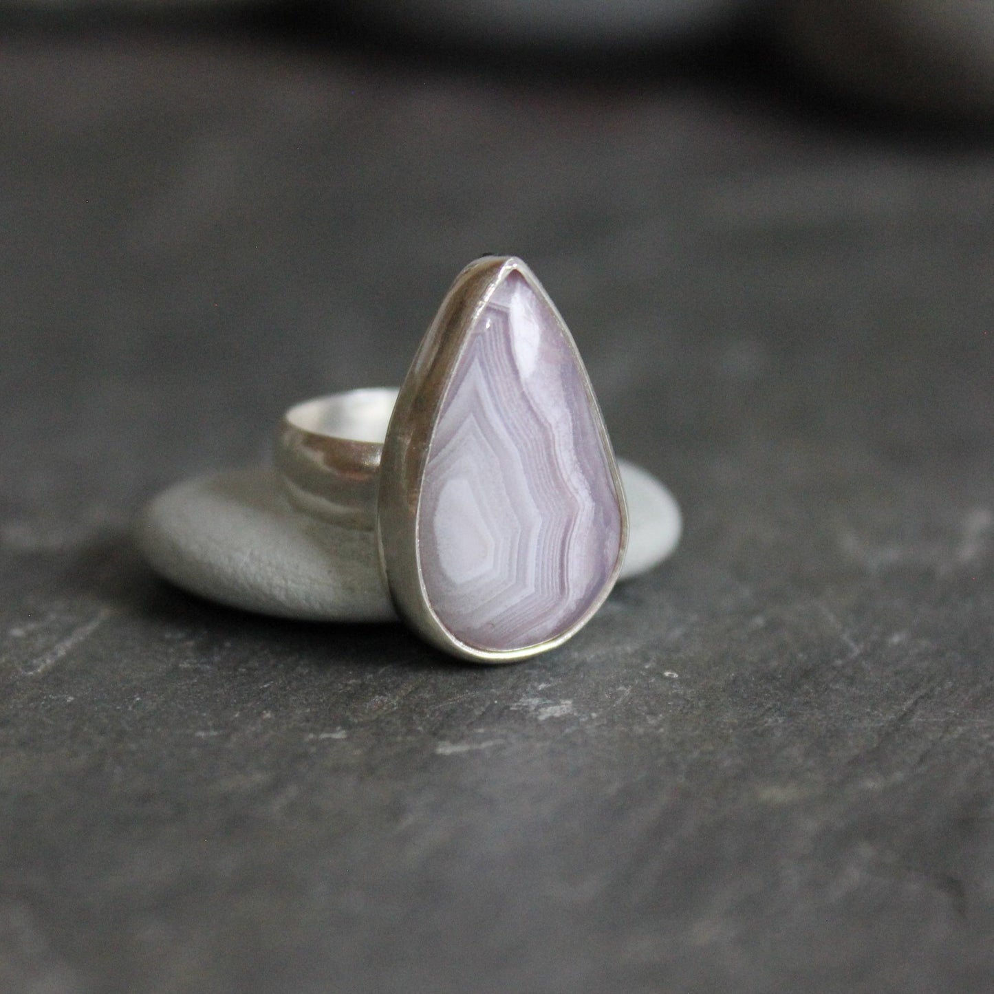 This is a teardrop agua nueva agate from Mexico that has banding and is set in a fine and sterling silver bezel setting on a sturdy silver band.  Size 4 1/4