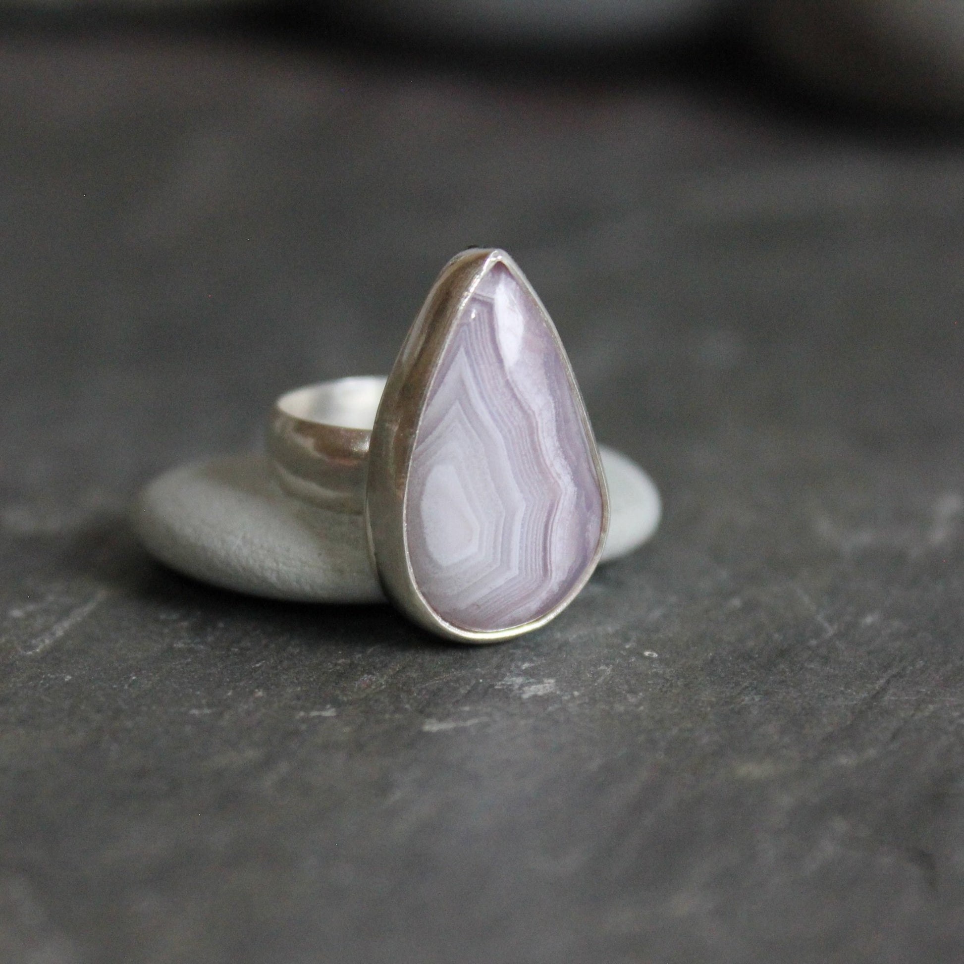 This is a teardrop agua nueva agate from Mexico that has banding and is set in a fine and sterling silver bezel setting on a sturdy silver band.  Size 4 1/4