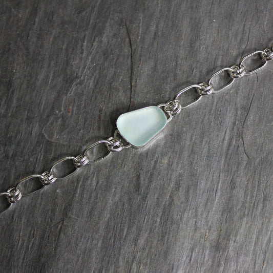This is a piece of light blue sea glass set in a fine & sterling silver bezel setting completed with a handmade oval link chain, finished to be a 7.5" bracelet. 
