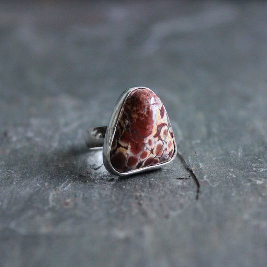 This is a red and cream Oregon jasper cabochon set in a sterling and fine silver bezel setting on a sturdy silver band.  Size 4.  The stone has red and cream colors and looks like poppy jasper. 