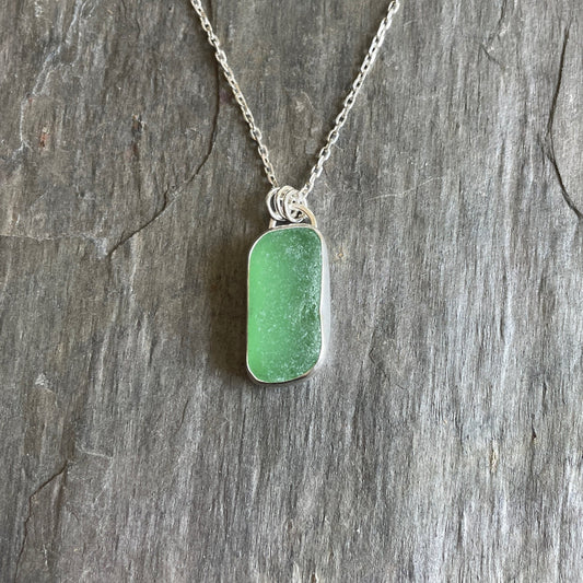 This is a rectangular piece of sage green sea glass set in a fine & sterling silver bezel setting on an 18" chain. 