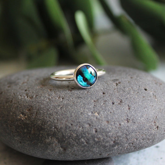 A 6mm or 8mm round dyed blue paua shell cabochon set in a sterling silver bezel. 