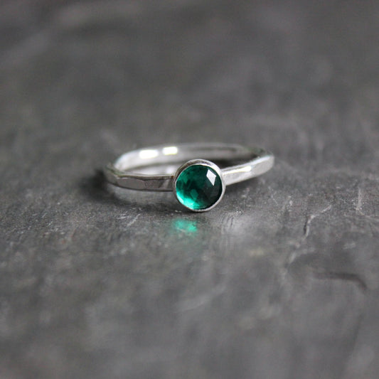 This is a 6mm rose cut lab-created emerald set in a sterling silver bezel on a sturdy silver band. 