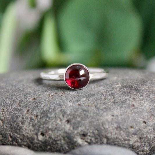 This is a 5-7mm round red garnet cabochon set in a sterling silver bezel setting on a sturdy silver band.  