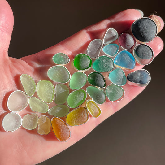 This is a handful of sea glass inside bezels during my process of making jewelry. All of the sea glass in our jewelry is found and never altered in any way. 