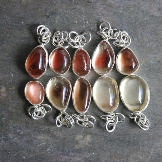 Oregon sunstone pendants displayed for sale in an Etsy shop and at a market booth.
