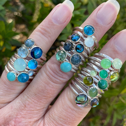 A selection of blue and green sterling silver gemstone stacking rings handmade by Accent Yourself.