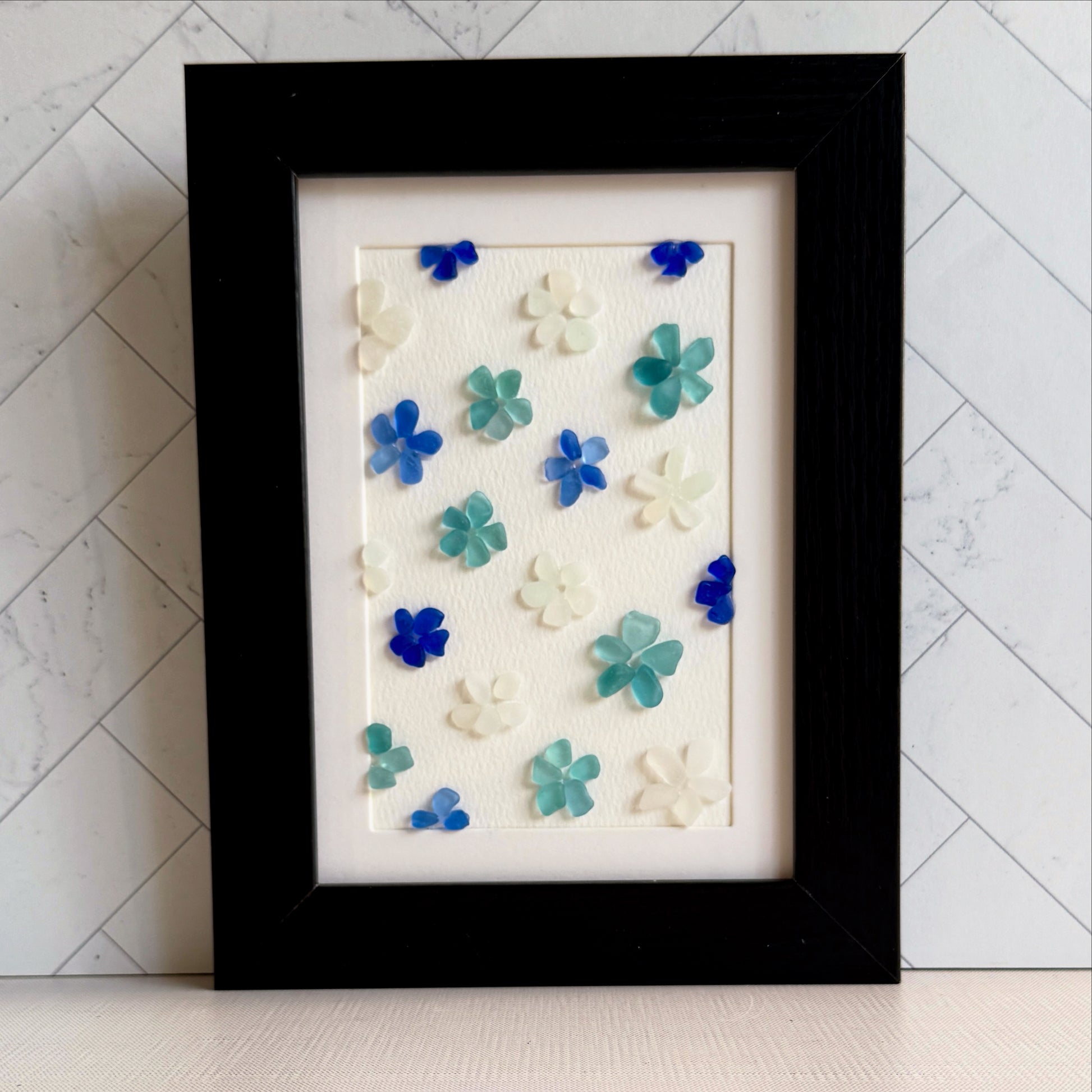 Framed artwork with blue and green floral patterns on a white background