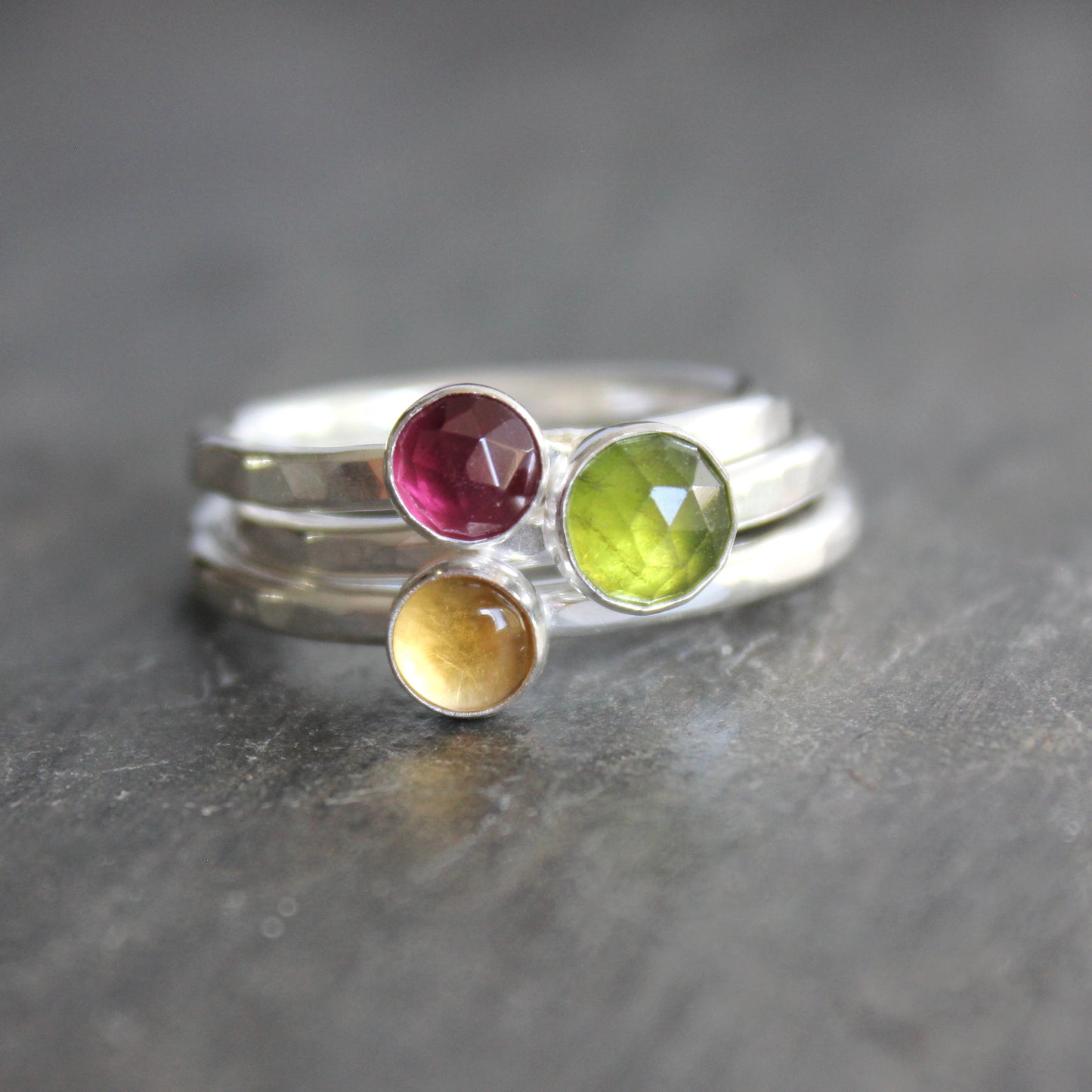Silver ring with multicolored gemstones on a dark surface rhodolite garnet citrine serpentine