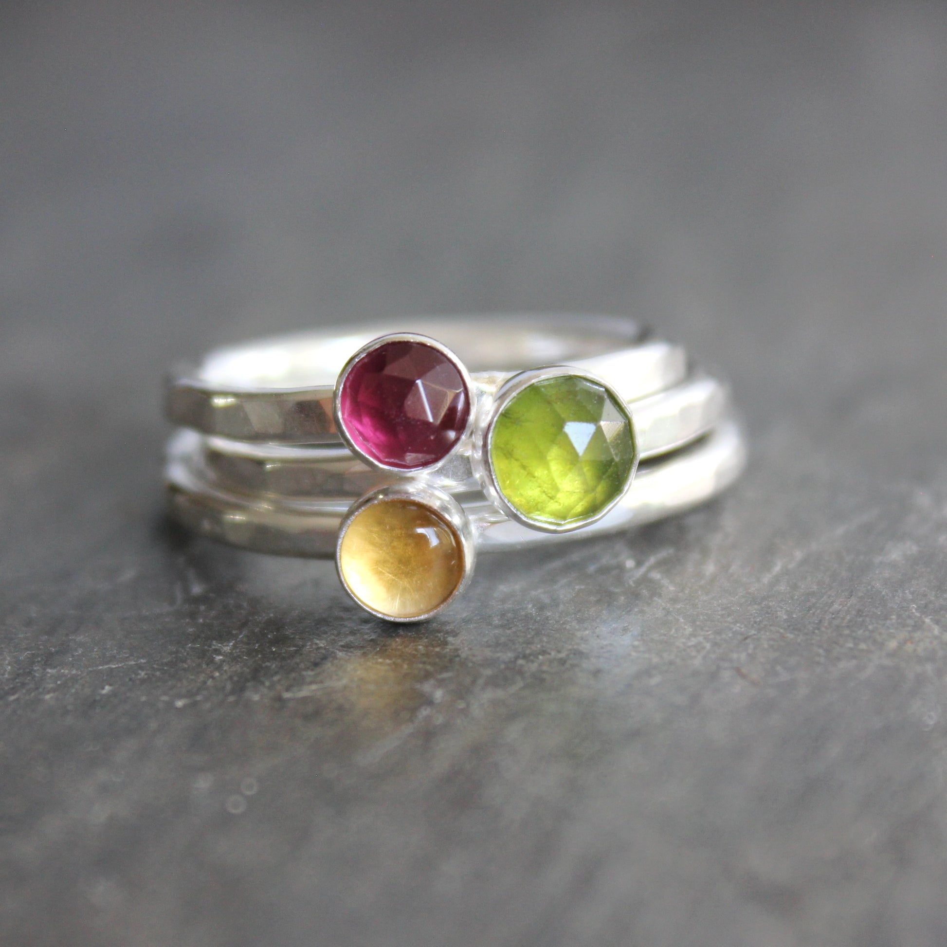 Silver ring with multicolored gemstones on a dark surface rhodolite garnet citrine serpentine