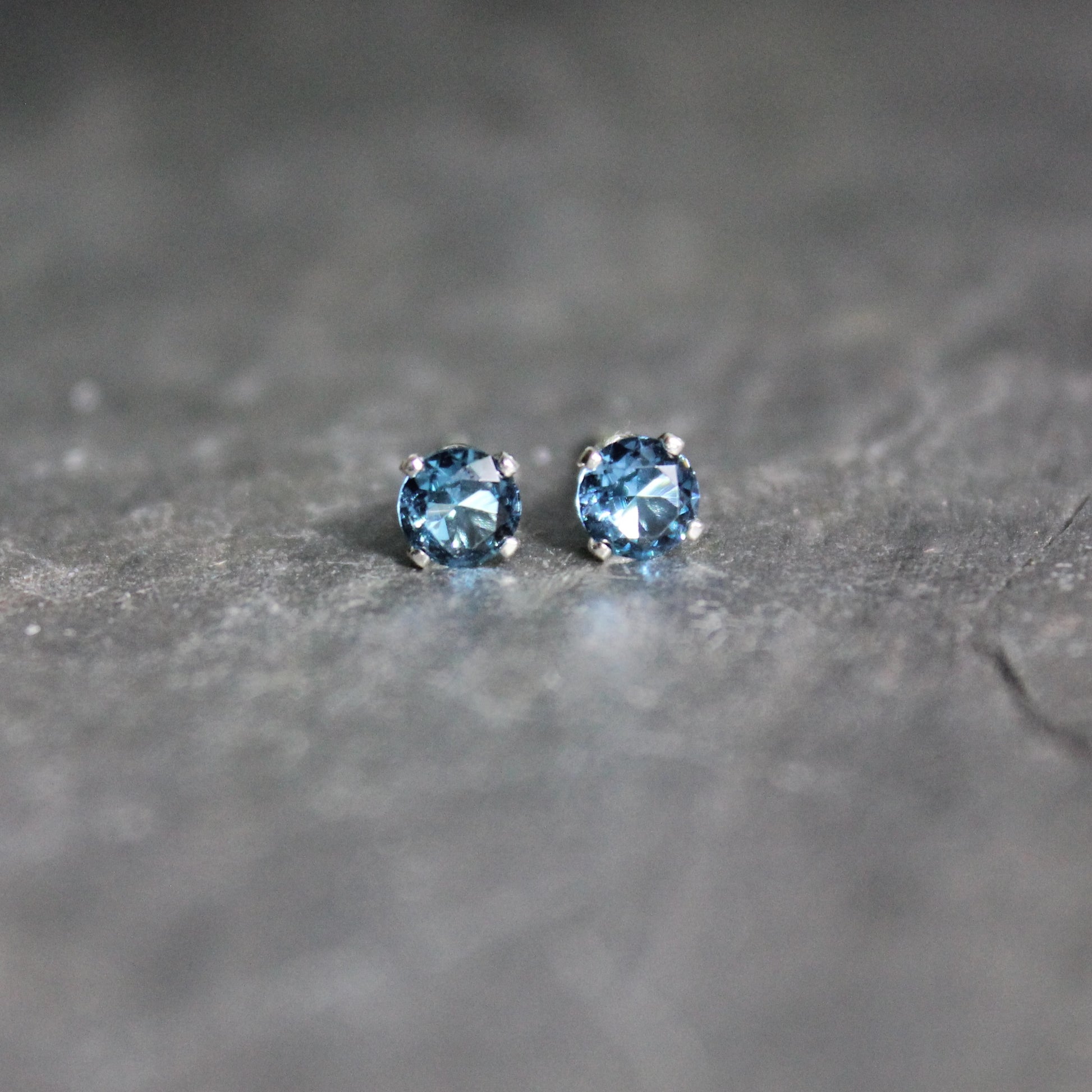 These stud earrings have 4mm round faceted lab created blue zircon set in sterling silver 4-prong earring settings with eariring backs. 