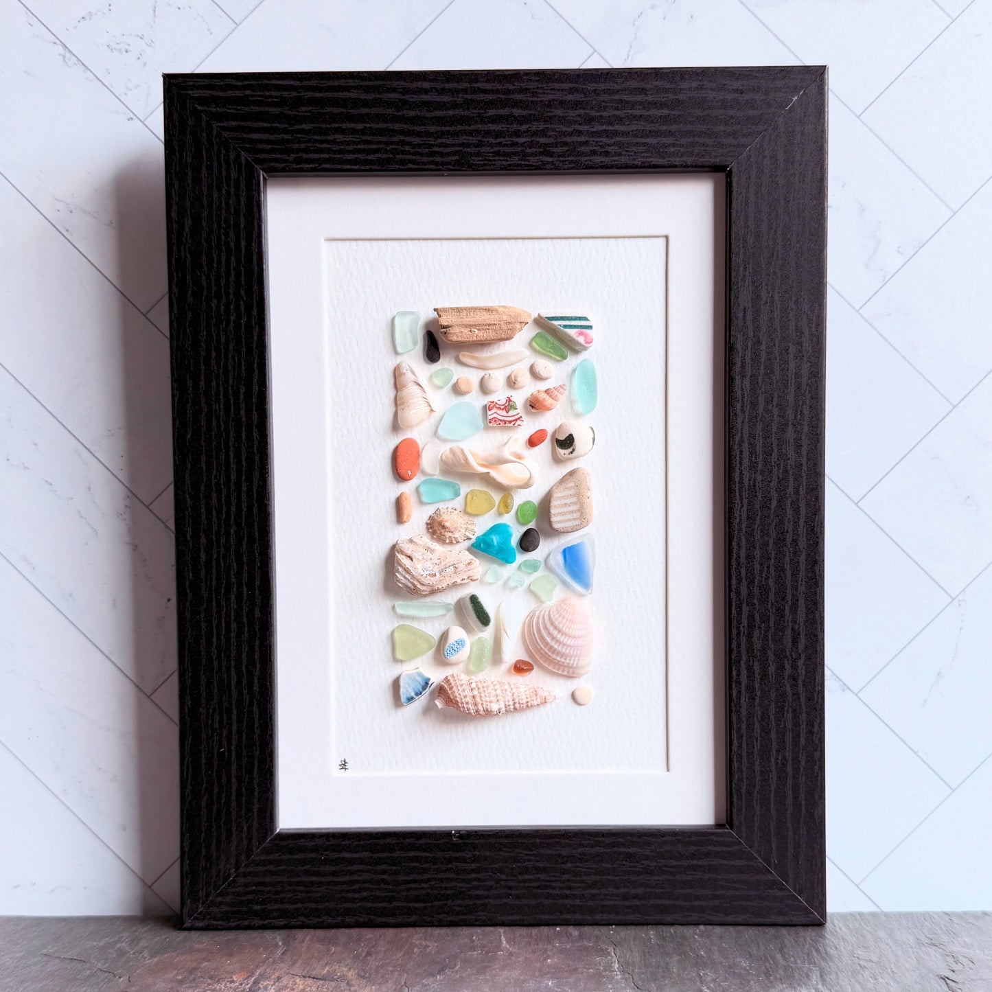 Framed artwork made of seashells on a white background