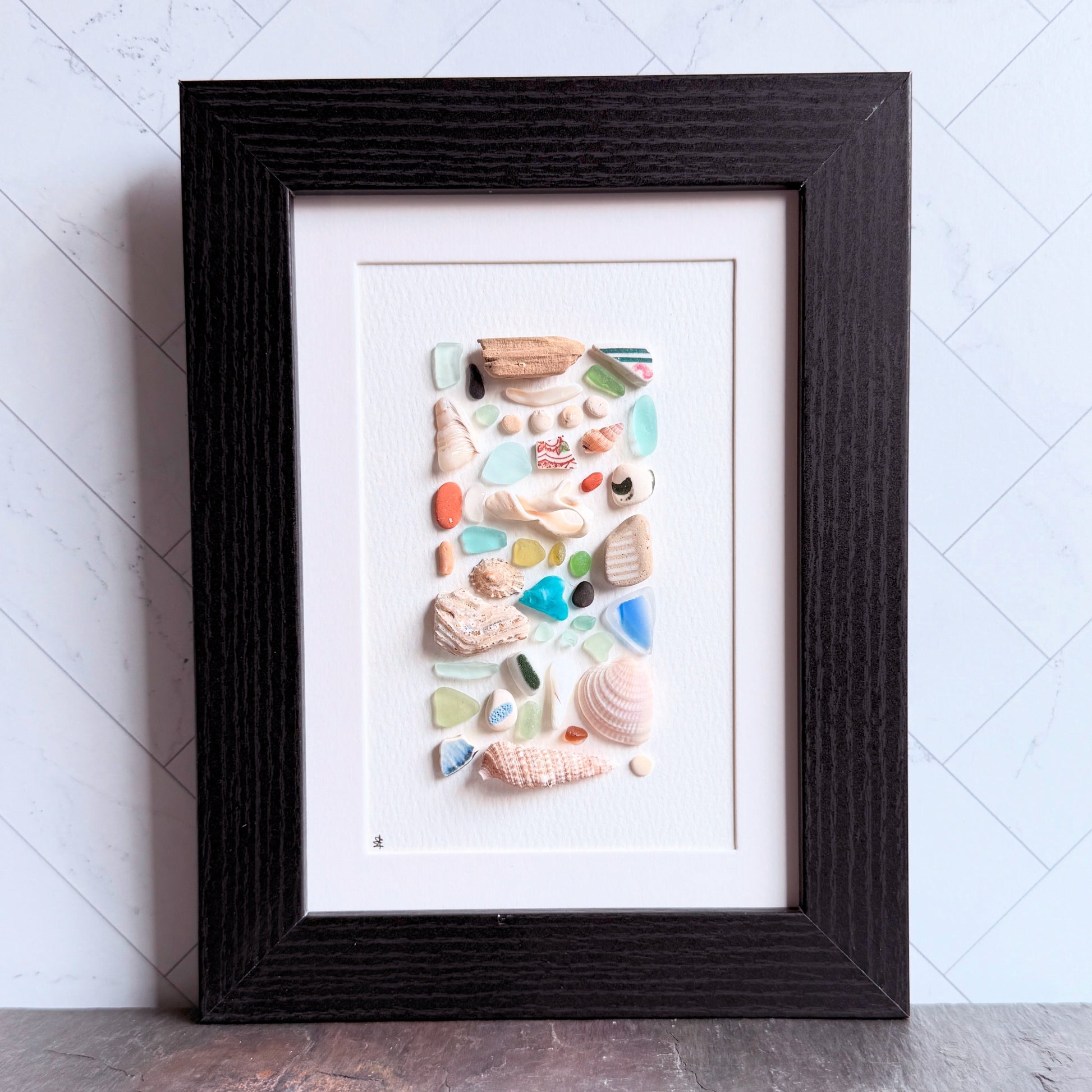 Framed artwork made of seashells on a white background