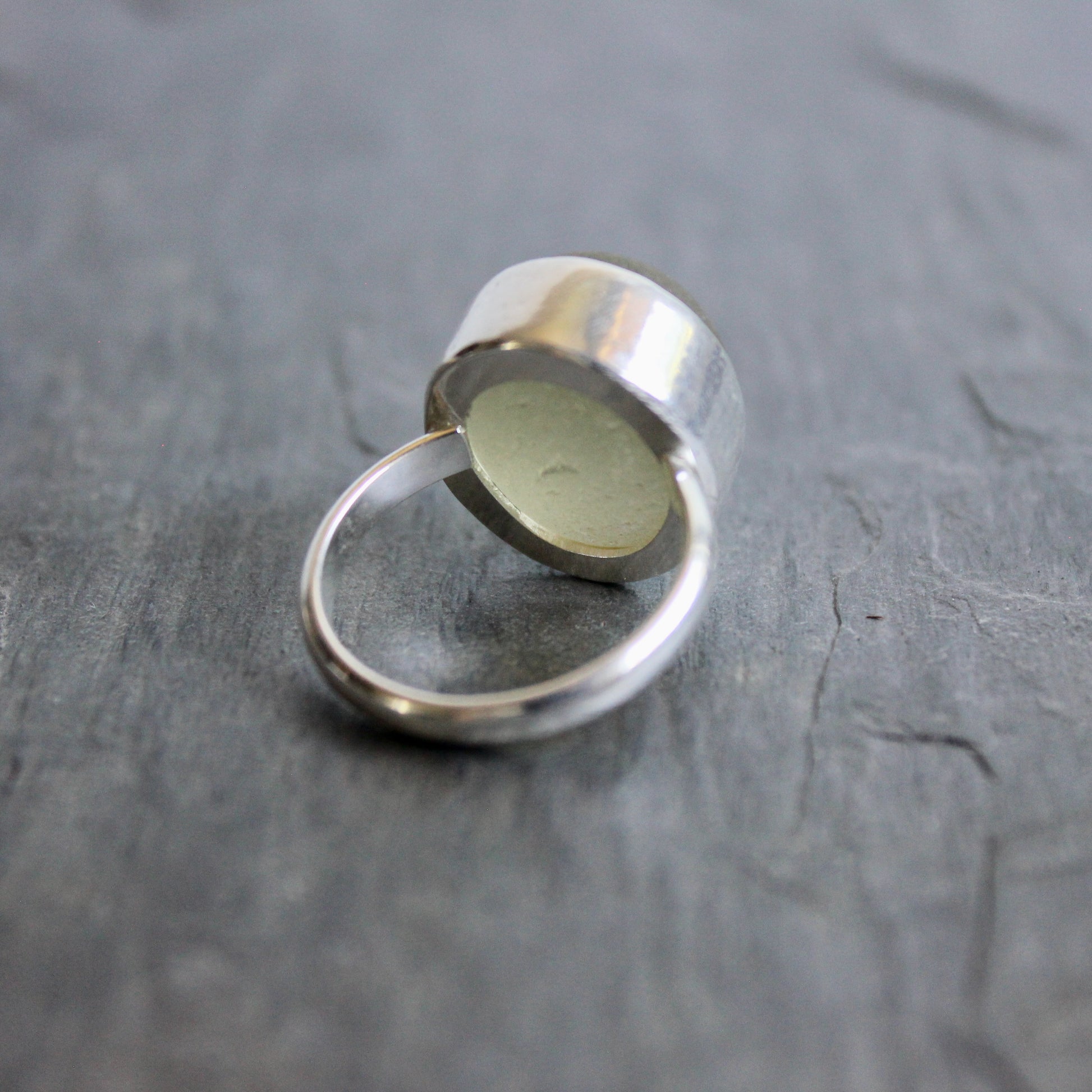 Silver ring with a circular Champagne Sea Glass ring on a gray surface