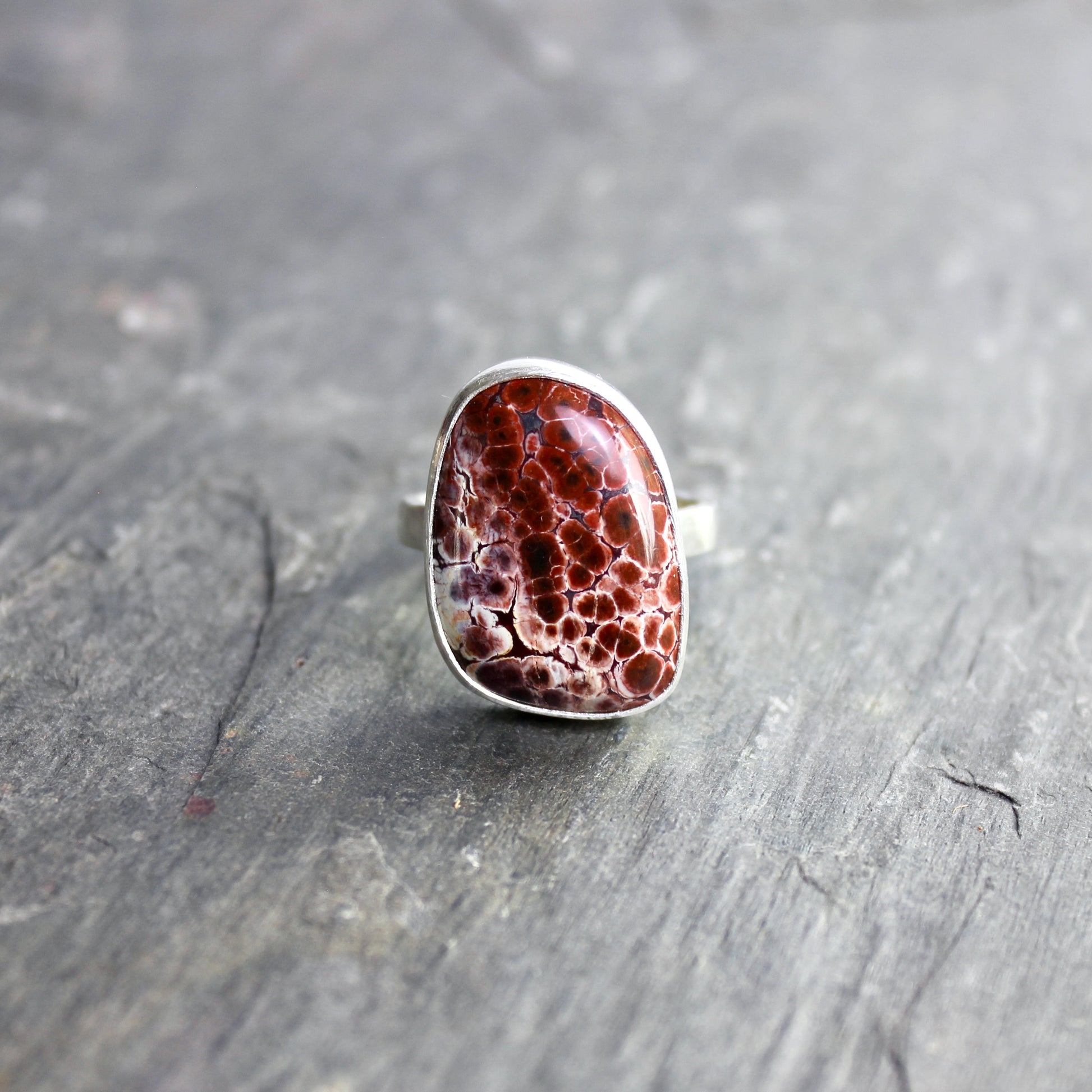 This pretty ring has a locally-sourced red Oregon orbicular jasper that is set in a fine and sterling silver bezel and on a sturdy silver hammered band. Handmade by Will Macy in Corvallis, OR.