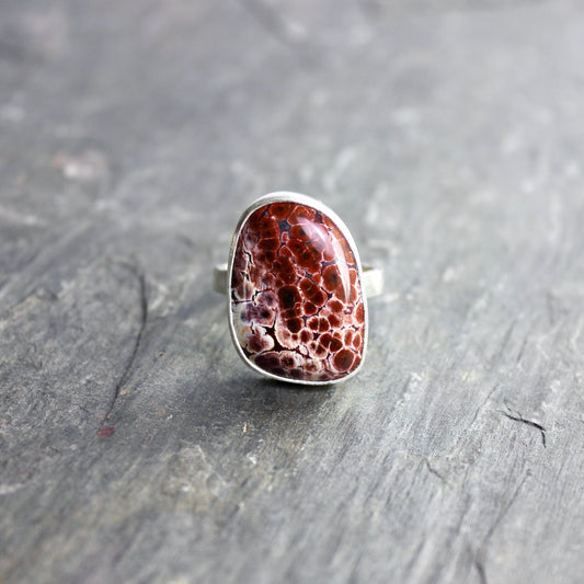 This pretty ring has a locally-sourced red Oregon orbicular jasper that is set in a fine and sterling silver bezel and on a sturdy silver hammered band. Handmade by Will Macy in Corvallis, OR.