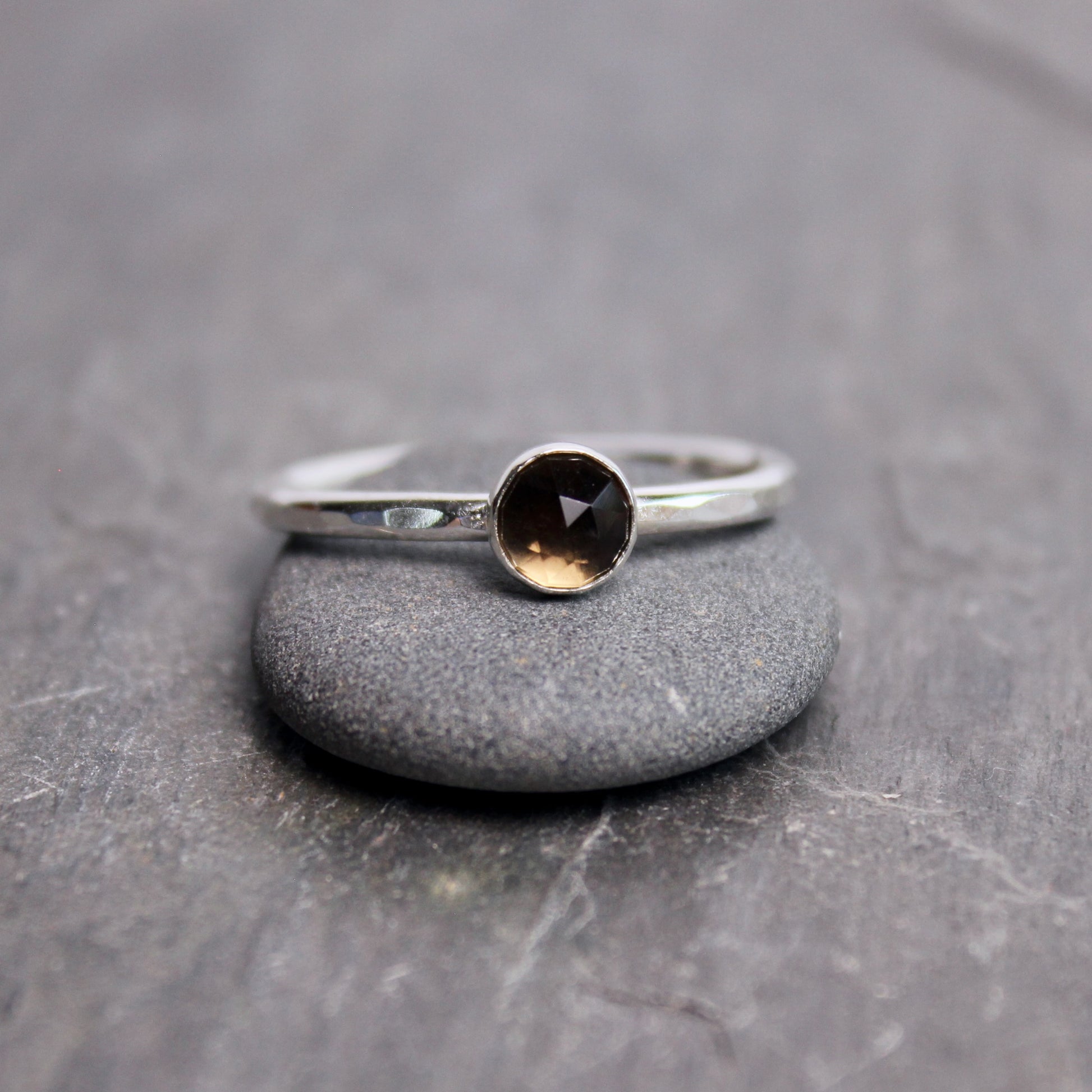 Silver ring with a black gemstone on a gray stone surface