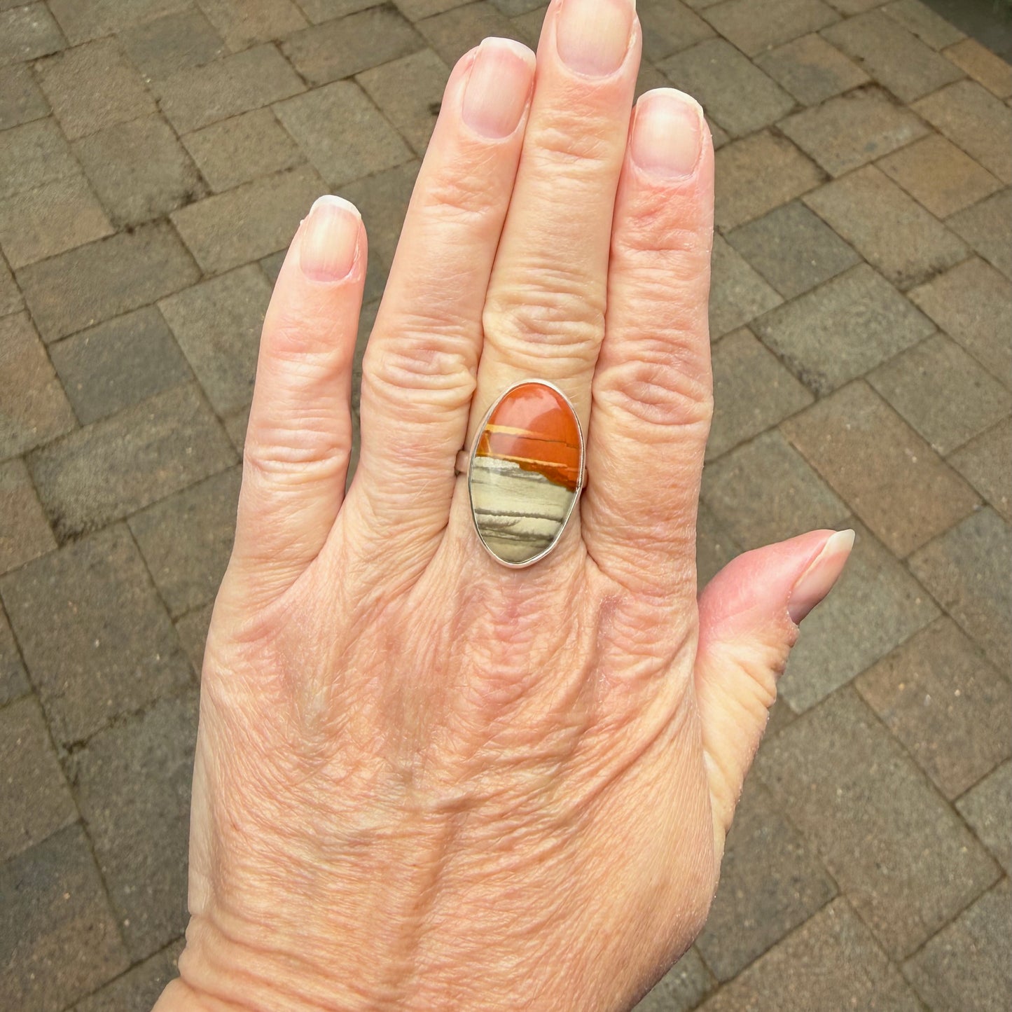 Handmade Oregon Landscape Jasper ring worn on hand, showing natural orange and gray stone patterns in sterling silver bezel setting
