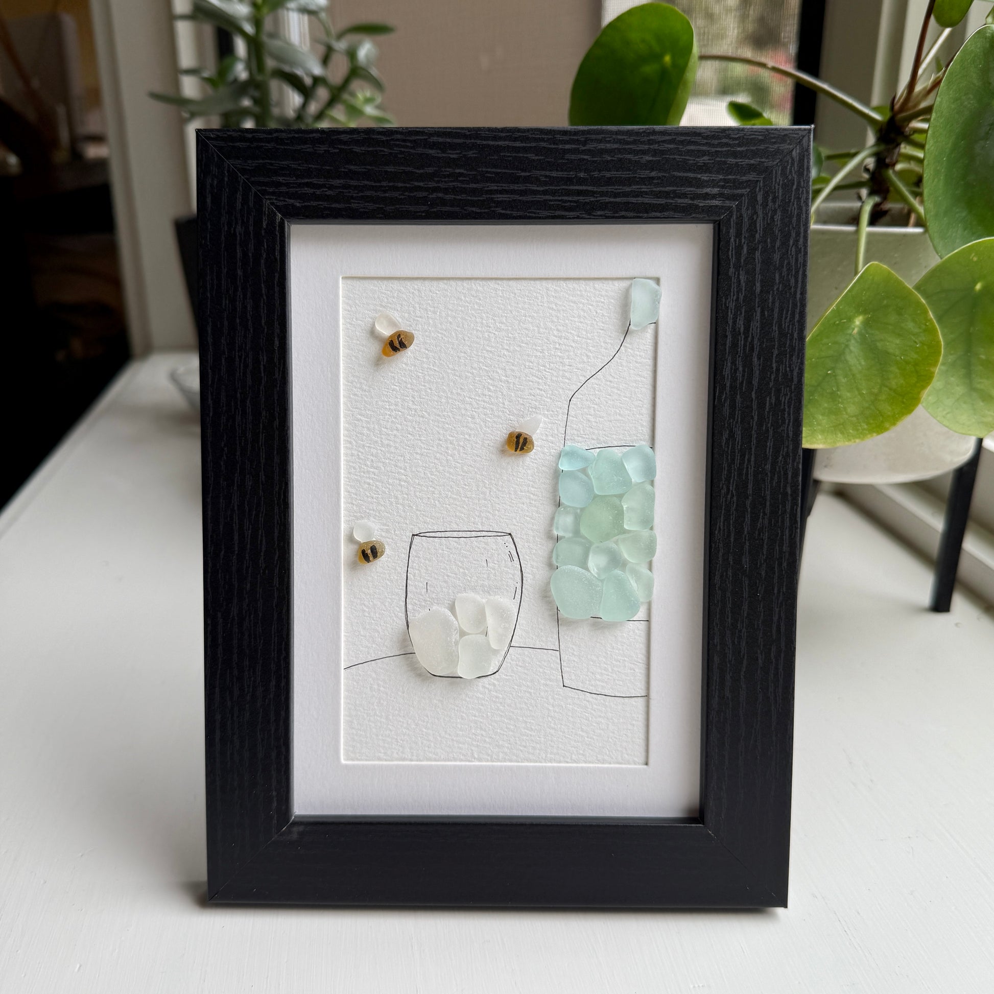 Framed artwork with pebble art design on a white background