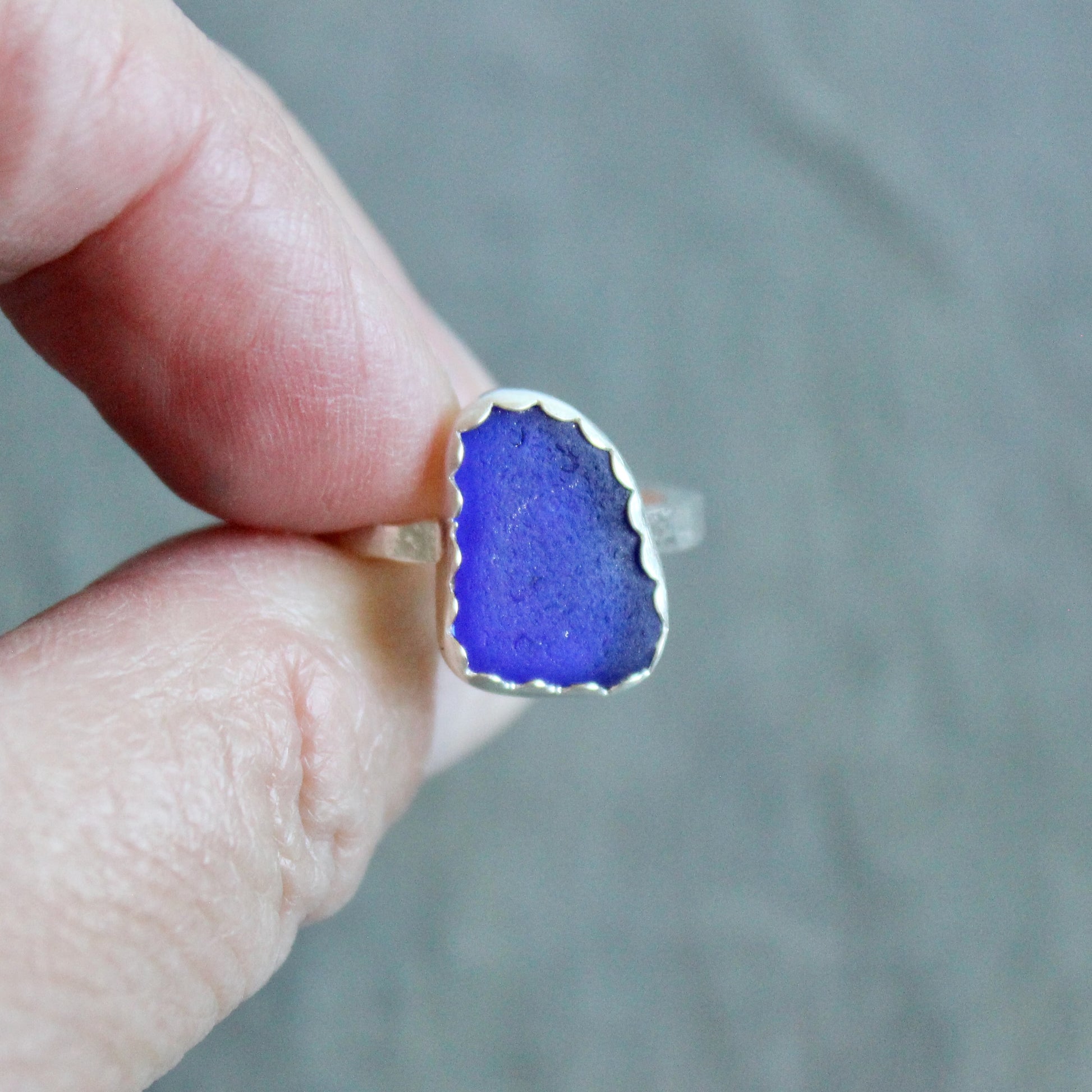Blue ring held by a hand against a gray background