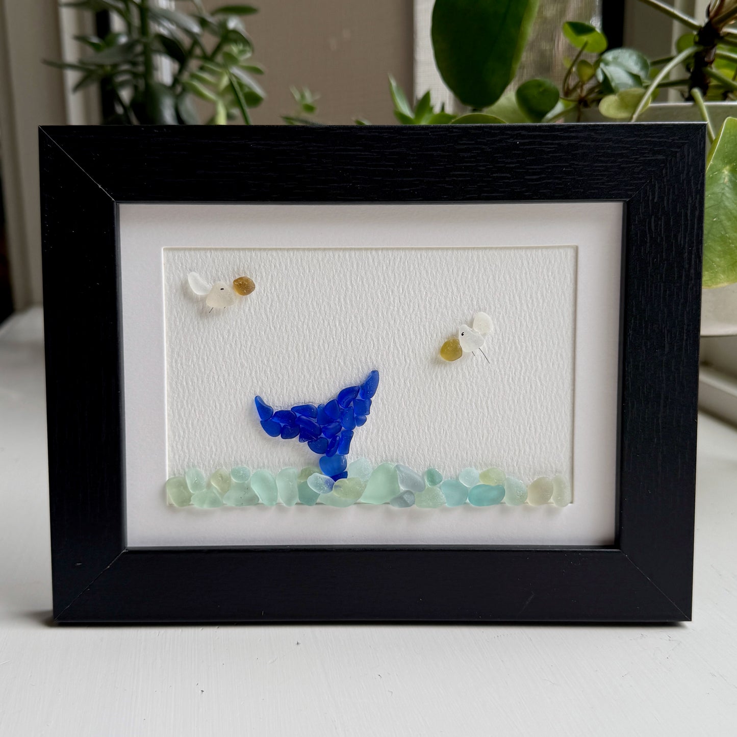 Framed artwork with a blue butterfly and white flowers on a white background