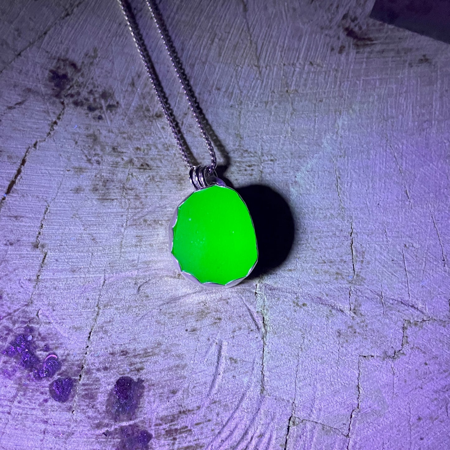 This pendant necklace has a bright green UV piece of sea glass that is set in a fine and sterling silver scalloped bezel on a sturdy silver chain. The uranium sea glass glows under a black light. Handmade by Barb Macy in Corvallis, OR