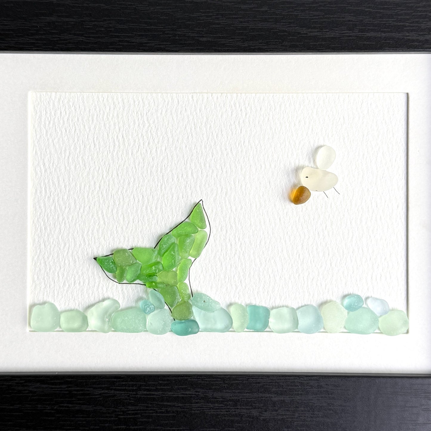Mosaic artwork of a green fish and a white shell on a white background