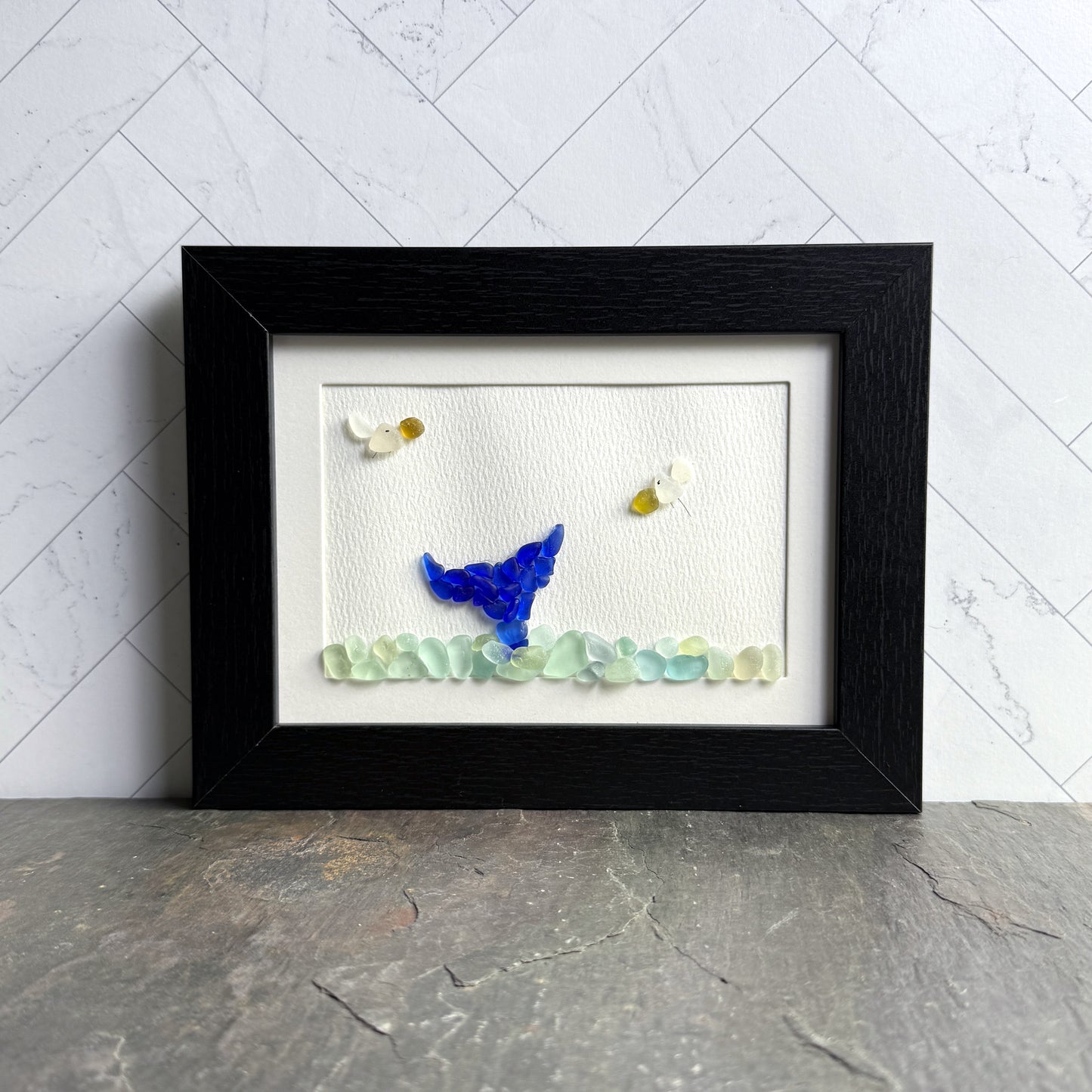 Framed artwork of a blue gnome with flowers on a white background