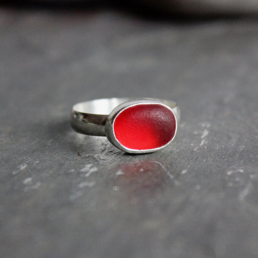 This ring has a piece of rare red sea glass set in a fine & sterling silver bezel setting on a hammered band.  Size 10