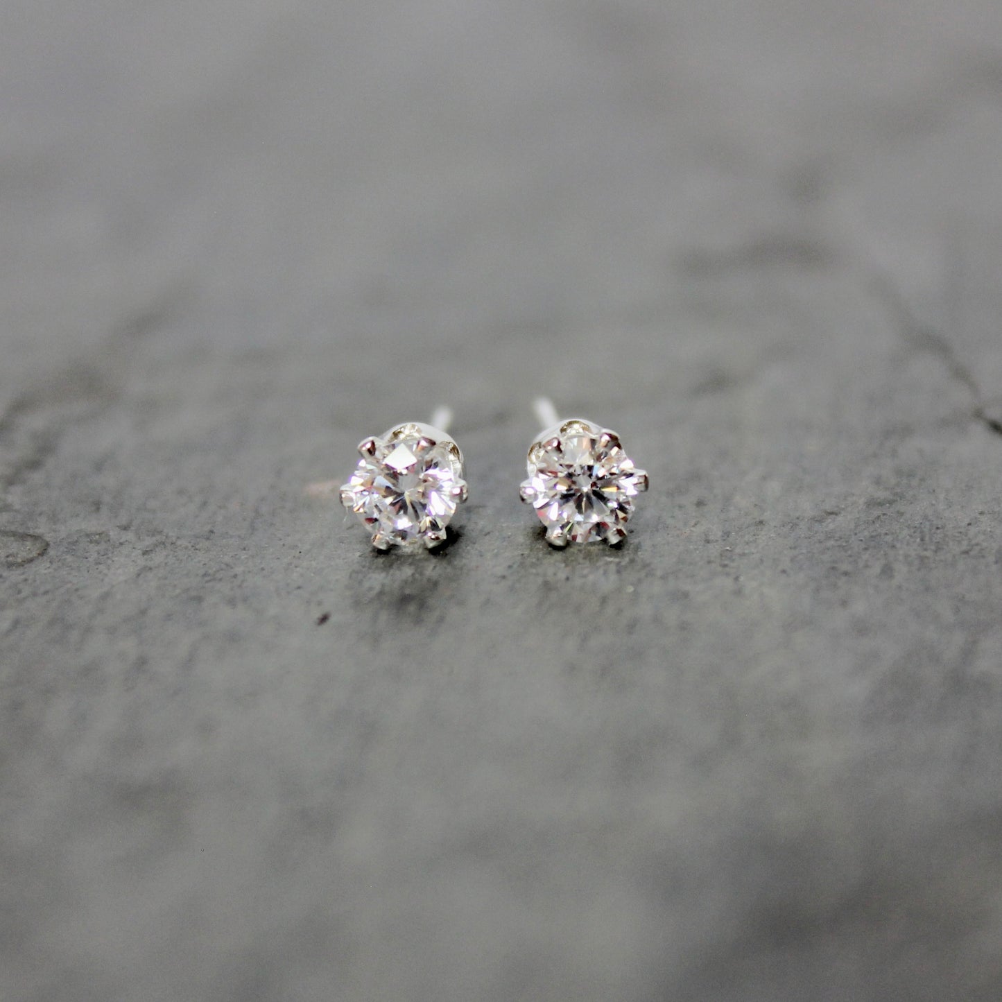 Pair of silver stud earrings on a gray surface