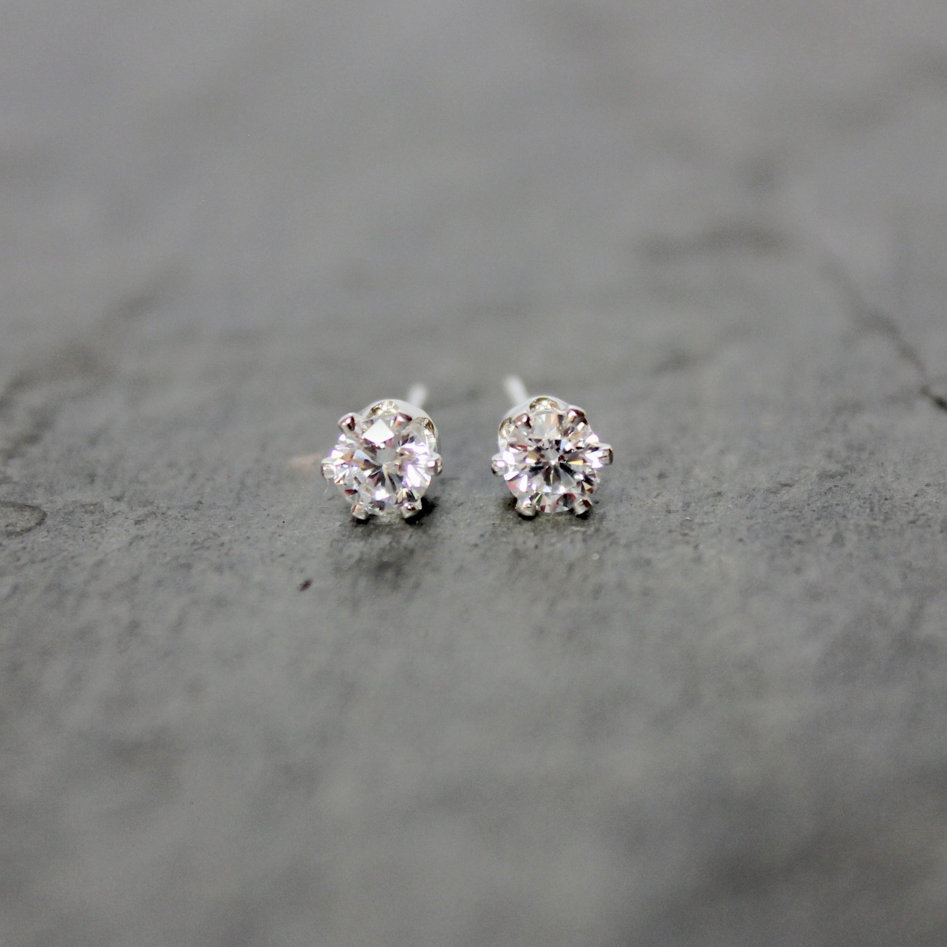 Pair of silver stud earrings on a gray surface