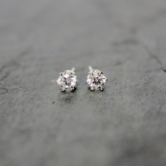 Pair of silver stud earrings on a gray surface