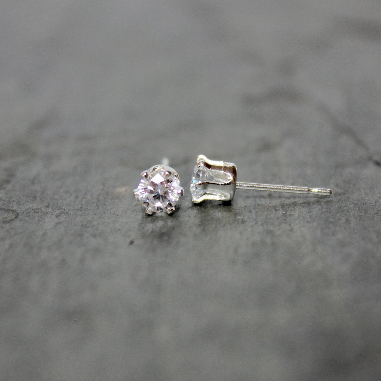 Silver stud earrings on a dark textured surface