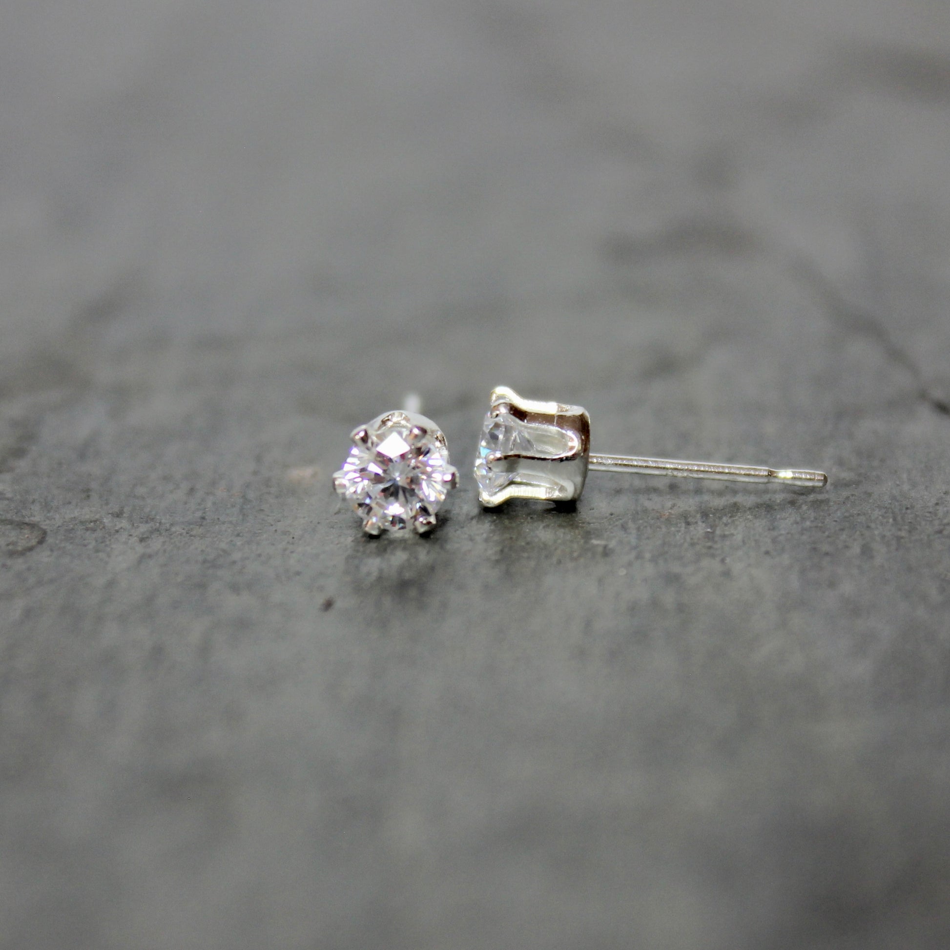 Silver stud earrings on a dark textured surface