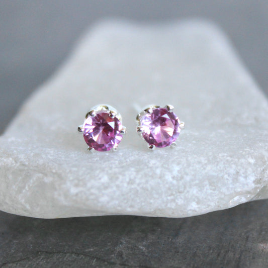 Purple gemstone stud earrings on a white stone with a gray background