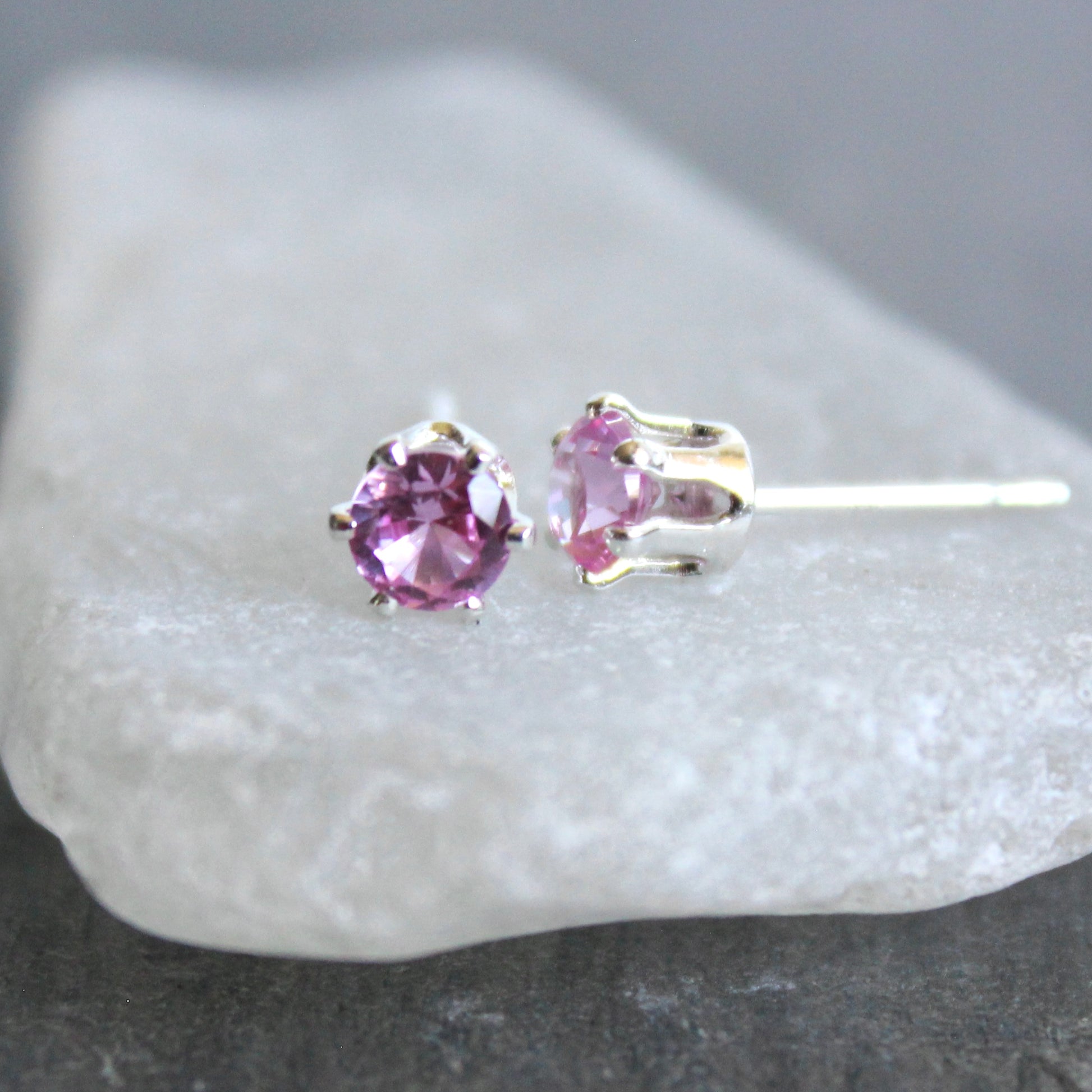 Pair of pink stud earrings on a white stone surface