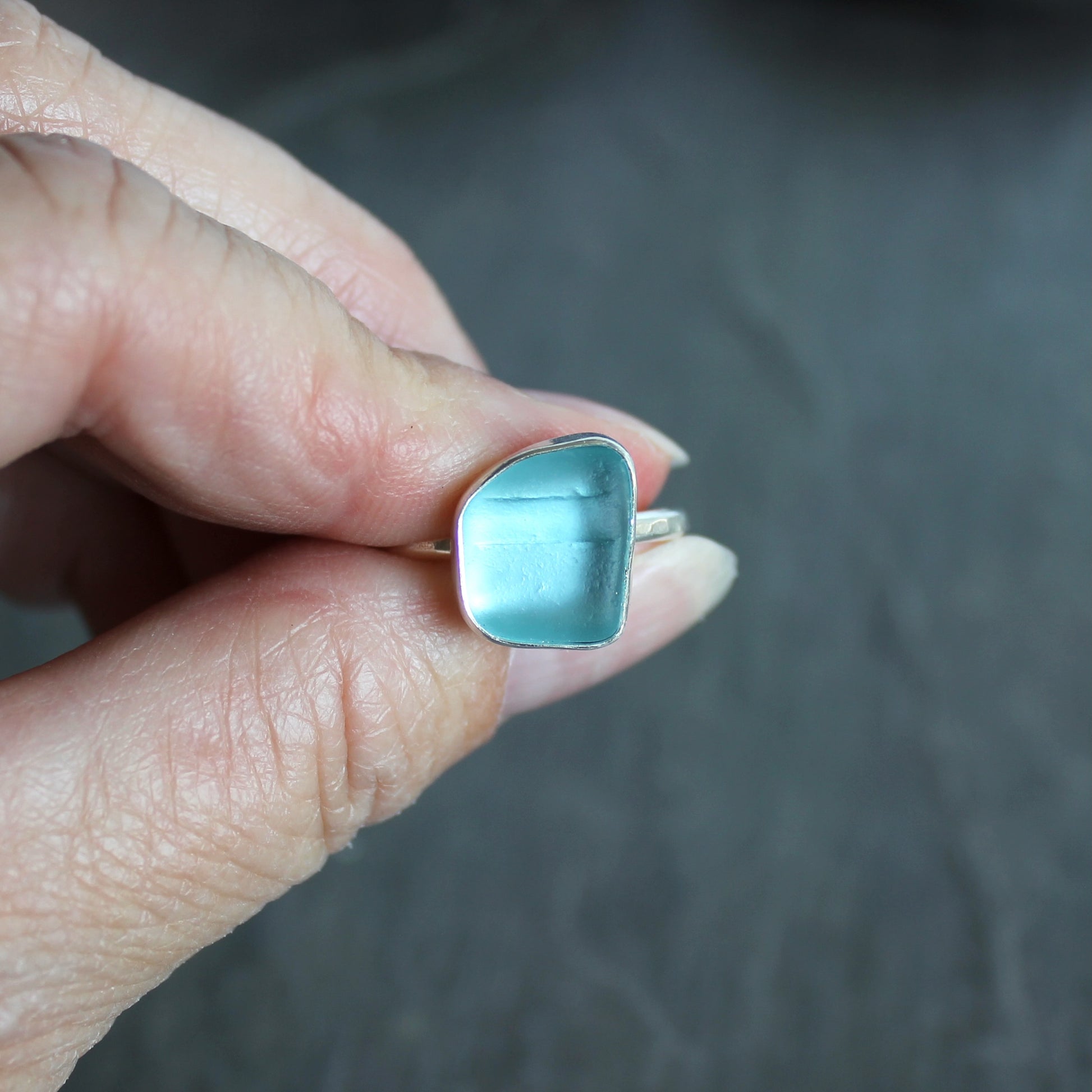 This ring has an aqua turquoise blue piece of sea glass that is set in a fine and sterling silver bezel setting on a sturdy hammered band. Size 8 3/4 Handmade by Barb Macy in Corvallis, Oregon.