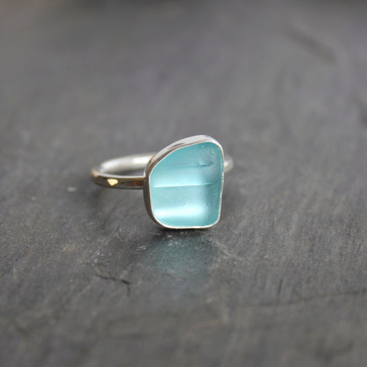This ring has an aqua turquoise blue piece of sea glass that is set in a fine and sterling silver bezel setting on a sturdy hammered band. Size 8 3/4 Handmade by Barb Macy in Corvallis, Oregon.